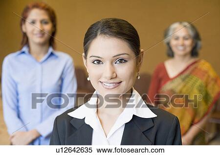 Portrait of a businesswoman smiling with two businesswomen standing behind her View Large Photo Image Stock Photography - Portrait of a businesswoman smiling with two businesswomen standing behind her. Fotosearch