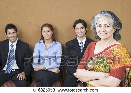 Portrait of a businesswoman standing with her arms crossed with three business executives sitting behind her View Large Photo Image Stock Image - Portrait of a businesswoman standing with her arms crossed with three business executives sitting behind her. Fotosearch