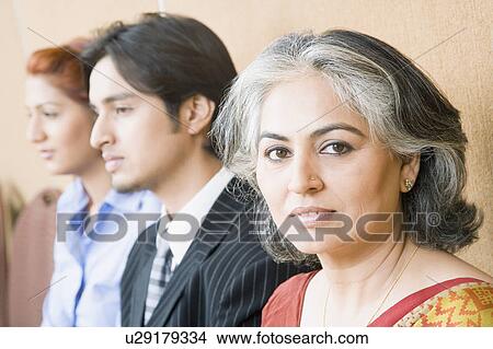 Picture - Portrait of a businesswoman with two business executives sitting beside her. Fotosearch