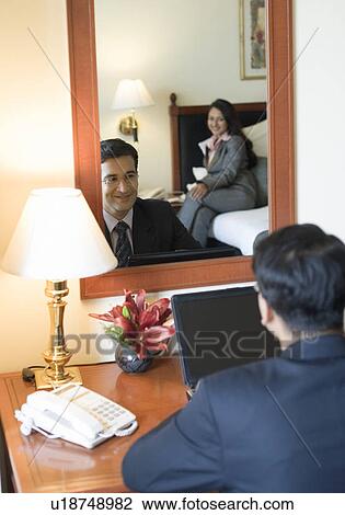 Rea view of a businessman using a laptop in front of a mirror View Large Photo Image Stock Image - Rea view of a businessman using a laptop in front of a mirror. Fotosearch
