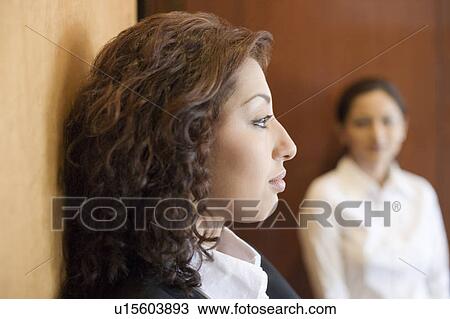 Side profile of a businesswoman thinking with another businesswoman standing in the background View Large Photo Image Stock Image - Side profile of a businesswoman thinking with another businesswoman standing in the background. Fotosearch