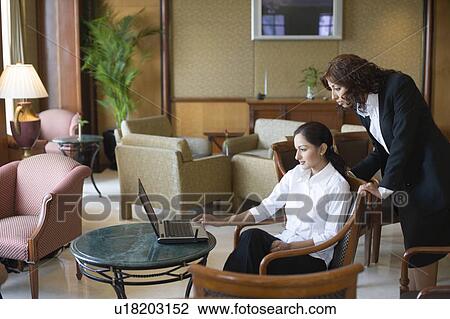 Side profile of two businesswomen looking at a laptop in a lobby View Large Photo Image Stock Image - Side profile of two businesswomen looking at a laptop in a lobby. Fotosearch
