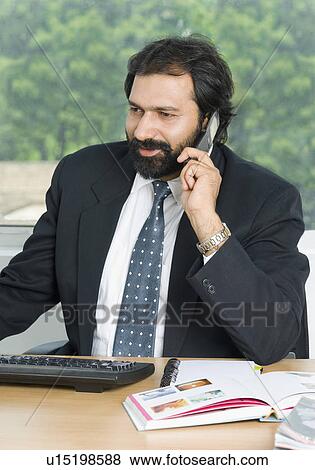 Businessman talking on a mobile phone and smiling View Large Photo Image Stock Photo - Businessman talking on a mobile phone and smiling. Fotosearch