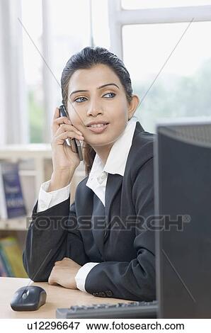 Businesswoman talking on a mobile phone an office View Large Photo Image Stock Photo - Businesswoman talking on a mobile phone an office. Fotosearch