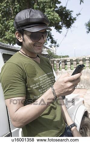 Close-up of a young man text messaging with a mobile phone and smiling, Goa, India View Large Photo Image Stock Photo - Close-up of a young man text messaging with a mobile phone and smiling, Goa, India. Fotosearch