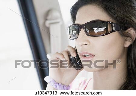 Close-up of a young woman talking on a mobile phone View Large Photo Image Stock Image - Close-up of a young woman talking on a mobile phone. Fotosearch