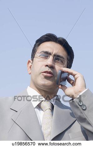 Stock Image - Low angle view of a businessman talking on a mobile phone. Fotosearch