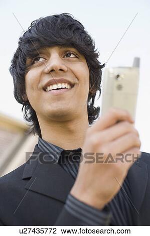 Low angle view of a teenage boy holding a mobile phone View Large Photo Image Stock Image - Low angle view of a teenage boy holding a mobile phone. Fotosearch