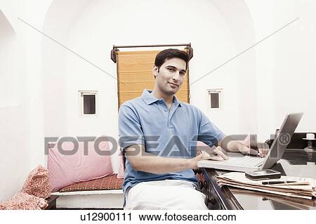 Portrait of a young man using a laptop View Large Photo Image Stock Image - Portrait of a young man using a laptop. Fotosearch
