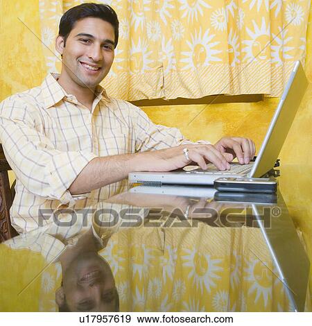 Portrait of a young man using a laptop and smiling View Large Photo Image Stock Photo - Portrait of a young man using a laptop and smiling. Fotosearch