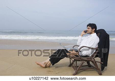Side profile of a businessman sitting in an armchair and talking on a mobile phone View Large Photo Image Stock Image - Side profile of a businessman sitting in an armchair and talking on a mobile phone. Fotosearch