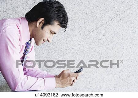 Side profile of a businessman text messaging on a mobile phone View Large Photo Image Stock Image - Side profile of a businessman text messaging on a mobile phone. Fotosearch