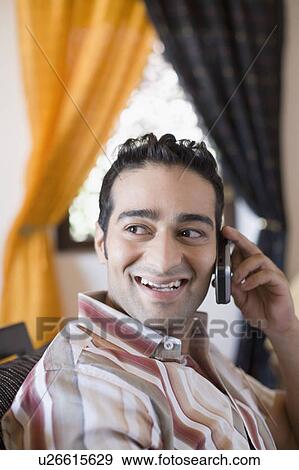 Side profile of a young man talking on a mobile phone and smiling View Large Photo Image Stock Photo - Side profile of a young man talking on a mobile phone and smiling. Fotosearch