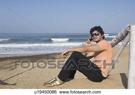 Side profile of a young man talking on a mobile phone and smiling View Large Photo Image Stock Photograph - Side profile of a young man talking on a mobile phone and smiling. Fotosearch