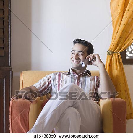 Young man talking on a mobile phone and smiling View Large Photo Image Stock Image - Young man talking on a mobile phone and smiling. Fotosearch