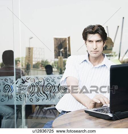 Stock Photography - Businessman using a laptop in a restaurant. Fotosearch