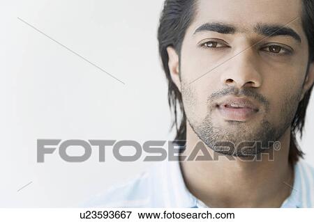 Close-up of a young man looking away View Large Photo Image Stock Photo - Close-up of a young man looking away. Fotosearch