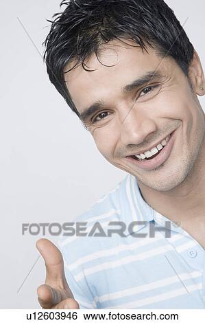 Portrait of a young man pointing and smiling View Large Photo Image Stock Photograph - Portrait of a young man pointing and smiling. Fotosearch