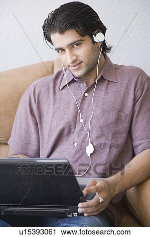 Portrait of a young man sitting in an armchair and using a laptop View Large Photo Image Stock Image - Portrait of a young man sitting in an armchair and using a laptop. Fotosearch
