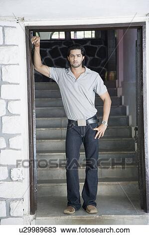 Portrait of a young man standing with his hand on his hip View Large Photo Image Stock Image - Portrait of a young man standing with his hand on his hip. Fotosearch