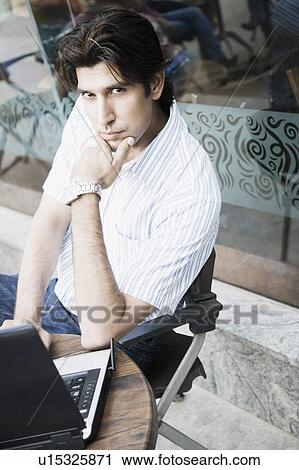 Portrait of a young man using a laptop in a restaurant View Large Photo Image Stock Image - Portrait of a young man using a laptop in a restaurant. Fotosearch