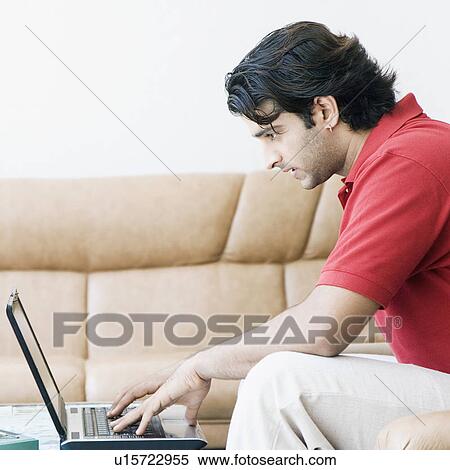 Side profile of a young man working on a laptop View Large Photo Image Stock Photography - Side profile of a young man working on a laptop. Fotosearch