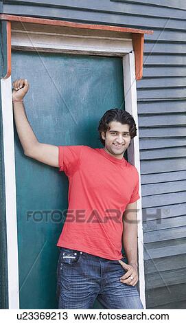 Young man leaning against a door and smiling View Large Photo Image Stock Image - Young man leaning against a door and smiling. Fotosearch