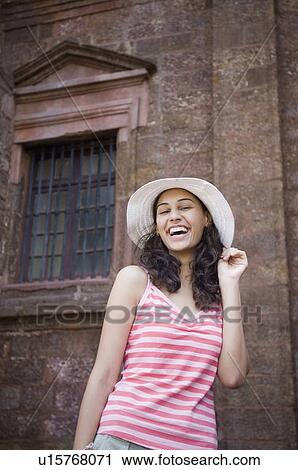 Stock Image - Low angle view of a young woman wearing a straw hat. Fotosearch
