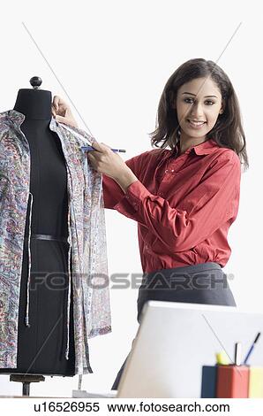 Portrait of a female fashion designer measuring length of a cloth View Large Photo Image Stock Photography - Portrait of a female fashion designer measuring length of a cloth. Fotosearch