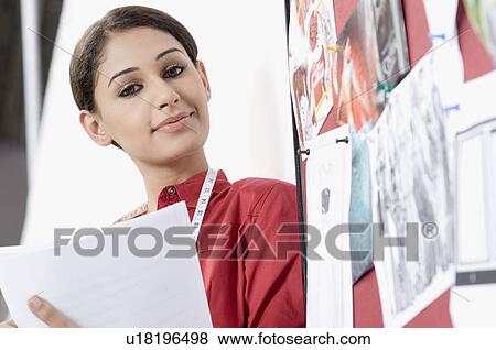Portrait of a young woman beside a mood board and smirking View Large Photo Image Stock Photo - Portrait of a young woman beside a mood board and smirking. Fotosearch