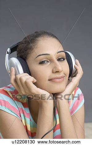 Stock Image - Portrait of a young woman listening to music and smirking. Fotosearch