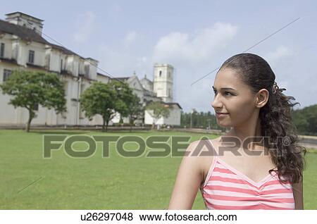 Stock Photo - Young woman smiling in front of a cathedral, Se Cathedral, Goa, India. Fotosearch