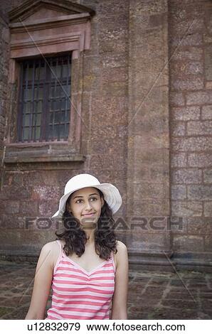 Stock Photo - Young woman smirking in front of a wall, Goa, India. Fotosearch