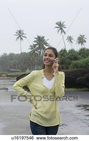 Young woman talking on a mobile phone on the beach View Large Photo Image Stock Photograph - Young woman talking on a mobile phone on the beach. Fotosearch