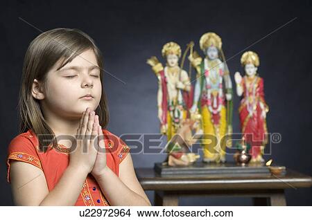 Close-up of a girl praying with statues of God beside her View Large Photo Image Picture - Close-up of a girl praying with statues of God beside her. Fotosearch