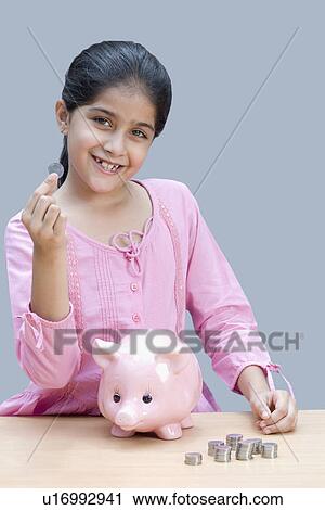 Stock Image - Portrait of a girl holding a coin and smiling. Fotosearch