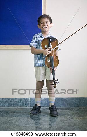 Stock Image - Portrait of a schoolboy holding a violin and smiling. Fotosearch