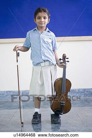 Portrait of a schoolgirl holding a violin with a bow View Large Photo Image Stock Photo - Portrait of a schoolgirl holding a violin with a bow. Fotosearch