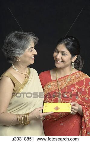 Close-up of a mature woman giving a gift to her daughter and smiling View Large Photo Image Stock Image - Close-up of a mature woman giving a gift to her daughter and smiling. Fotosearch