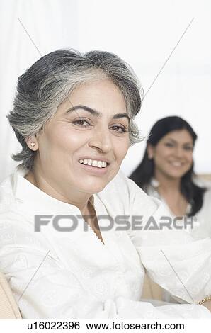 Stock Photograph - Close-up of a mature woman smiling with her daughter in the background. Fotosearch