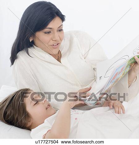 Girl reading a book with her mother View Large Photo Image Picture - Girl reading a book with her mother. Fotosearch