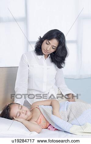 Girl sleeping on the bed with her mother sitting near her View Large Photo Image Stock Photo - Girl sleeping on the bed with her mother sitting near her. Fotosearch