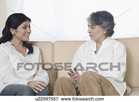 Mature woman and her daughter sitting on a couch and talking to each other View Large Photo Image Stock Photo - Mature woman and her daughter sitting on a couch and talking to each other. Fotosearch