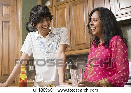Stock Image - Mature woman smiling with her son in the kitchen. Fotosearch