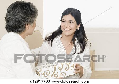 Mid adult woman giving a gift to her mother and smiling View Large Photo Image Stock Image - Mid adult woman giving a gift to her mother and smiling. Fotosearch