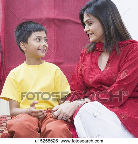 Stock Photograph - Mid adult woman holding her son's hand and smiling. Fotosearch