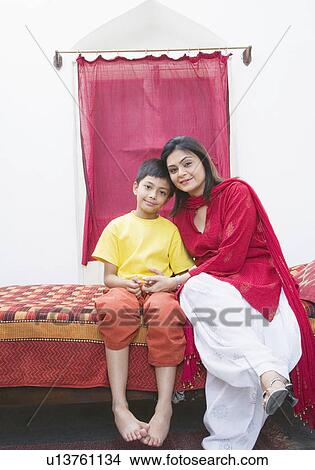 Portrait of a boy with his mother sitting on the bed View Large Photo Image Picture - Portrait of a boy with his mother sitting on the bed. Fotosearch