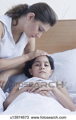 Portrait of a girl lying on the bed and her mother sitting beside her View Large Photo Image Stock Image - Portrait of a girl lying on the bed and her mother sitting beside her. Fotosearch
