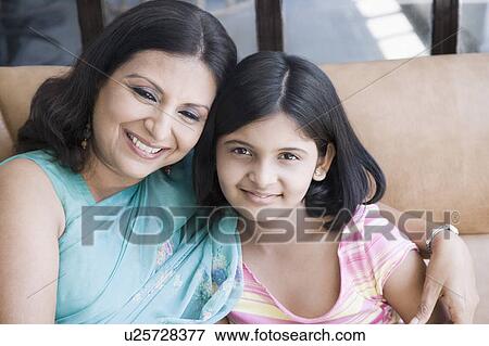 Portrait of a girl sitting on a couch with her mother View Large Photo Image Stock Photo - Portrait of a girl sitting on a couch with her mother. Fotosearch