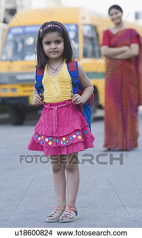 Portrait of a girl standing on the road with her teacher standing in the background View Large Photo Image Picture - Portrait of a girl standing on the road with her teacher standing in the background. Fotosearch